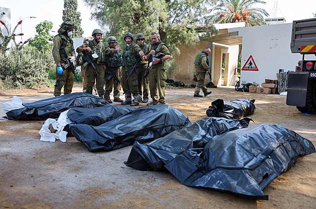 Vojáci odnáejí tla obtí masakru Hamásu v Kfar Aza.