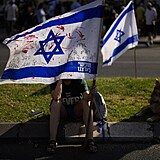 ena dr  izraelskou vlajku popsanou ervenou barvou bhem protestu, v nm se...