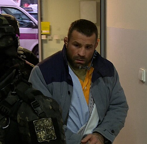 Do budovy m��� v doprovodu p��slu�n�k� v�ze�sk� slu�by.