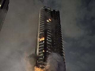 Po��r vysok� budovy v Dubaji po �toku. Plameny �lehaj� u pob�e�� a nad m�stem...