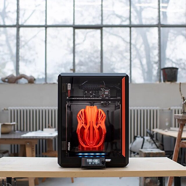 Tisk�rna Prusa Core One v pracovn�m prost�ed�. Dnes u� podobn� stroje stoj� nejen v gar��ch, ale i v kancel���ch nebo design�rsk�ch studi�ch.