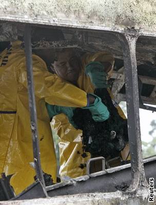 Záchranái vytahují z vypáleného autobusu kus zuhelnatlé obti.