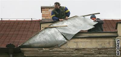 Mui opravují uvolnný lem stechy v Plzni.