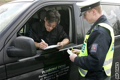 Policista a idi pohebního vozu u pejezdu u Kaznjova.