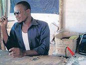 Gilbert z botswanského Ghanzi opravuje mobily ve stánku z vlnitého plechu.