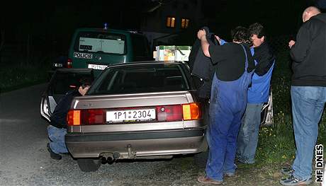 Policie prohledává auto mue, kterého mla neprávem za vraha (v monterkách).