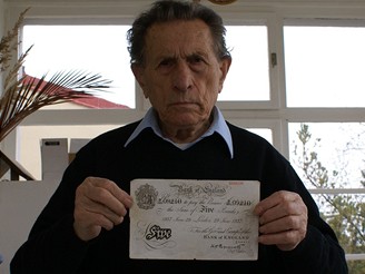 Adolf Burger drží v ruce falešnou librovou bankovku