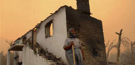 Obyvatelka vesnice Akbas stojí ped domem, který zniily plameny