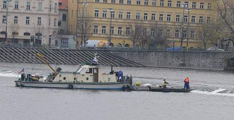 Pracovníci Povodí Vltavy vyproují desku z kontejneru, která spadla v pondlí z vrtulníku do Vltavy 