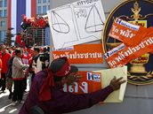 Thajský vládní stoupenec vylepuje plakáty na bránu správního soudu v Bangkoku. (2.12.2008)