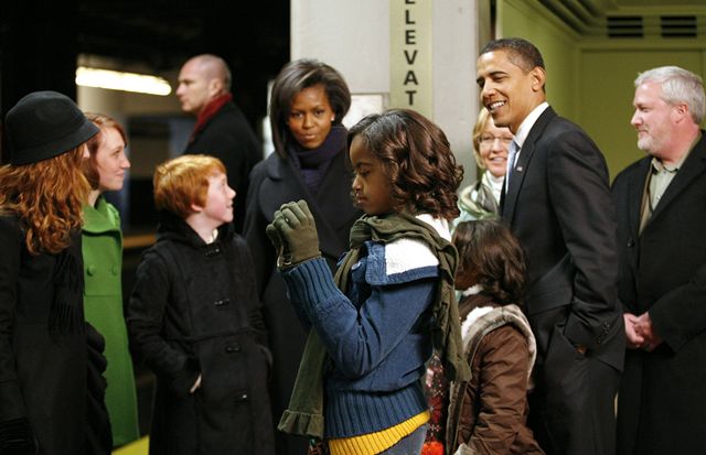 Barack Obama a jeho manelka Michelle mávají tisícm lidí kolem trati.