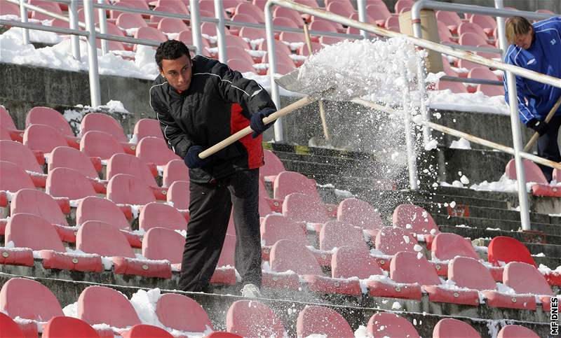 Fotbalisté 1. FC Brno uklízí sníh ze sedaek stadionu na Srbské