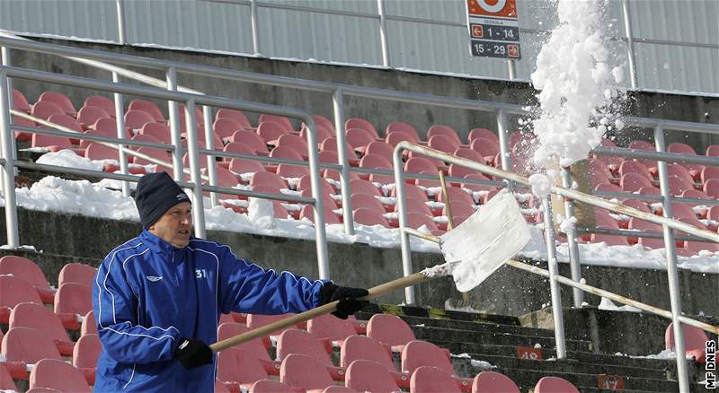 Fotbalisté 1. FC Brno uklízí sníh ze sedaek stadionu na Srbské