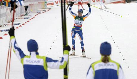 Finská běžkyně na lyžích Aino Kaisa Saarinenová se raduje před cílem štafety, kde ji čekají parťačky.
