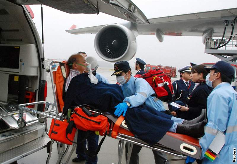 Záchranái penáejí na tokijském letiti pasaéra letadla Northwest Airlines, který se zranil pi turbulencích. (20. únor 2009)