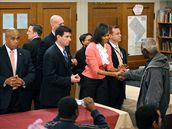 První dáma Spojených stát Michelle Obamová obklopena ochrankou si tese rukou s jedním z chydých, kterým vydávala ve tvrtek ve vyvaovn pro chudé ve Washingtonu jídlo. (5. bezen 2009)