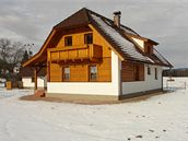 Hladký bílý pás soklu a náro�í zajímav� kontrastují s roubenou strukturou