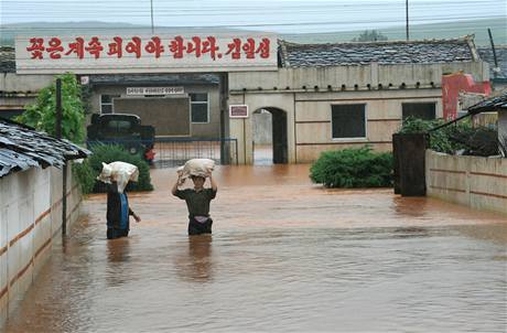 Severokorejci si zaplavenmi ulicemi severokorejskho msta Song odnej potravinovou pomoc od OSN 