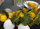 Zelenolutooranovou kombinaci projasují bílé vázy ve tvaru koule, pryskyníky a minigerbery ladí s citrony a malými pomeraníky kumkvaty. Vtviky s nádechem nazlátlého mechu ve barevn dokreslují,  voavé tóny dodávají bylinky, pedevím rozmarýna. 