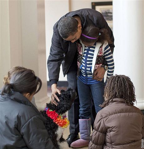 Barack Obama v objetí s dcerou Maliou hladí psíka Bo (12. dubna 2009)