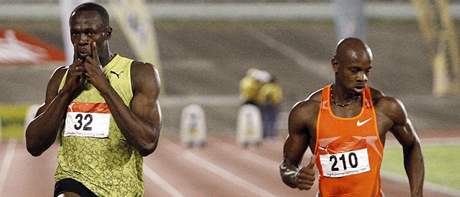 Usain Bolt si na jamajském ampionátu dovolil vítzné gesto jet na trati. Vpravo finiuje Asafa Powell.