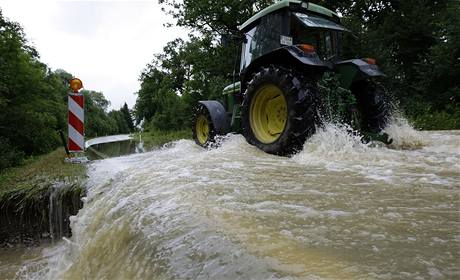 Traktor se sna projet zatopenou ulice v bersee na jihu Nmecka