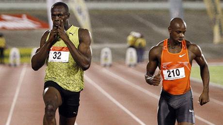 Usain Bolt si na jamajském ampionátu dovolil vítzné gesto jet na trati. Vpravo finiuje Asafa Powell.