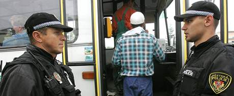 Stráníci hlídají, zda cestující dodrují nové pravidlo, podle kterého mohou nastupovat do autobusu jen pedními dvemi.
