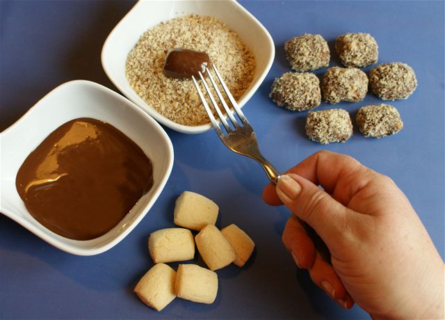 Upečené a zchladlé ořechy máčejte v rozehřáté čokoládě a hned je obalte v jemné ořechové strouhance. 