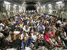 Tém 200 obyvatel Port-au-Prince sedí v dopravním letadle americké armády a míí na letit v Orlandu v USA. (18. ledna 2010)