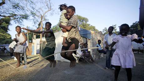 Dti skáou pes vihadlo v provizorním stanovém táboe na okraji Port-au-Prince. (22. ledna 2010)