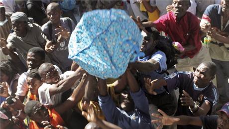 Lidé chytají pytle s potravinami, které jim z kamiónu házejí haittí vojáci. (29. ledna 2010)
