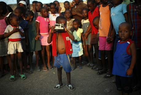 Haitský chlapec fotí v provizorním táboe pro peiví v Port-au-Prince