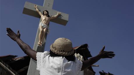�ena stojí p�ed k�í�em na Haiti a modlí se v den výro�í jednoho m�síce od zem�t�esení