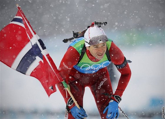 Ole Einar Björndalen se s norskou vlajkou v ruce raduje ze zlaté medaile, kterou vybojoval spolu se svými týmovými kolegy ve tafetovém závod biatlonist.