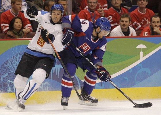 Ville Peltonen z Finska atakuje slovenského hokejistu Andreje Sekeru v zápase o tetí místo na ZOH ve Vancouveru.