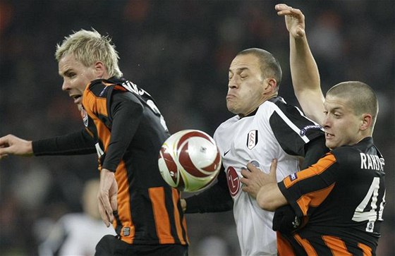 Tomá Hübschman (vlevo) se spoluhráem Rakytským bojují v dresu achtaru Donck s protihráem z Fulhamu; z utkání Evropské ligy  
