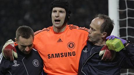 Zraněný Petr Čech z Chelsea opouští zápas za pomoci maséra a lékaře.
