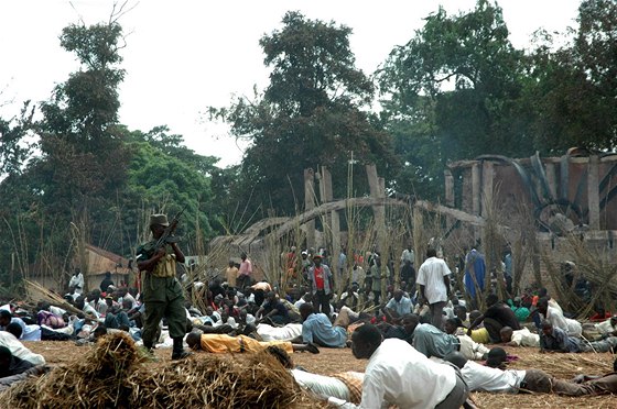 Ugandský voják hlídkuje ped ohoelými ruinami královských hrobek v Kasub, kolem se krí obyvatelé bugandského království.