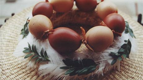 Slámový vnec staí dozdobit jemným bílým peím a zelenými snítkami.