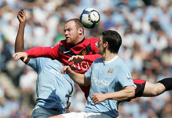 HLAVIKOVÝ SOUBOJ. Útoník Wayne Rooney z Manchesteru United (v erveném) se pere v hlavikovém souboji o mí s Garethem Barrym z Manchesteru City.