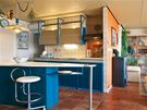 Kuchyn v modrém ladní, která navazuje na obývací pokoj, má také ocelovou konstrukci a vybetonovanou pracovní desku