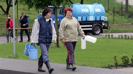 Lidé z Ústí na Perovsku míjí zásobník s pitnou vodou, pistavený kvli záplavám (19. kvtna 2010)
