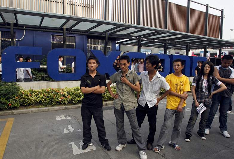 Zamstnanci tchajwanského výrobce mobil Foxconn. se shromádili ped vstupem do továrního komplexu.