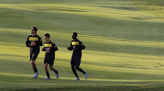 Braziltí fotbalisté Kaká, Josue a Ramires (zleva) vyklusávají pi tréninku po golfovém hiti.