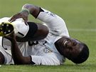 AU! Ghanský fotbalista Asamoah Gyan se svíjí na trávníku s bolestivou grimasou. Sklání se nad ním srbský soupe Branislav Ivanovi. 