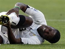 AU! Ghansk fotbalista Asamoah Gyan se svj na trvnku s bolestivou grimasou. Skln se nad nm srbsk soupe Branislav Ivanovi. 