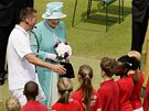 Anglická královna Albta II. se v tenisovém areálu ve Wimbledonu zdraví s malými podavai mík
