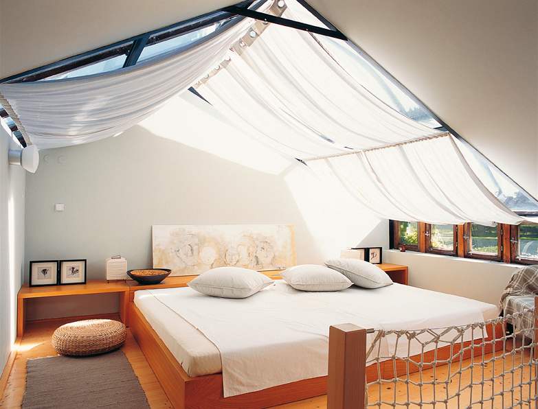 Hostinský pokoj s impozantní postelí, nad níž se vyjímá lněný zastiňovací závěs