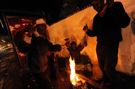 Bezdomovci v Johannesburgu se hej u zaplenho ohn.